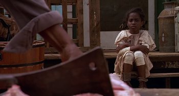 Movie still from “Fried Green Tomatoes” (1991), directed by Jon Avnet – A young girl sitting on a chair next to an ax; Medium shot, Over the shoulder angle
