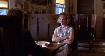 Movie still from “Fried Green Tomatoes” (1991), directed by Jon Avnet – A woman sitting at a table with her arms crossed; Medium shot, Over the shoulder angle