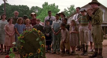Movie still from “Fried Green Tomatoes” (1991), directed by Jon Avnet – A group of people standing around a grave with sunflowers; Wide shot, Over the shoulder angle