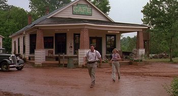 Movie still from “Fried Green Tomatoes” (1991), directed by Jon Avnet – A man and a woman are running in front of a cafe; Wide shot, Low angle