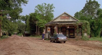 Movie still from “Fried Green Tomatoes” (1991), directed by Jon Avnet – An older woman walks down a dirt road past an old store; Extreme Wide shot, Low angle