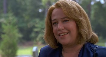 Movie still from “Fried Green Tomatoes” (1991), directed by Jon Avnet – A person wearing a suit and smiling; Close Up shot, Over the shoulder angle