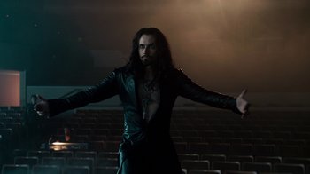 Movie still from “Fright Night” (2011), directed by Craig Gillespie – A man with long black hair is standing in front of a movie screen; Wide shot, Low angle
