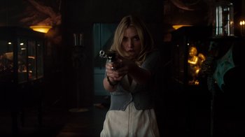 Movie still from “Fright Night” (2011), directed by Craig Gillespie – A woman is holding a gun in a dark room; Medium shot, Over the shoulder angle