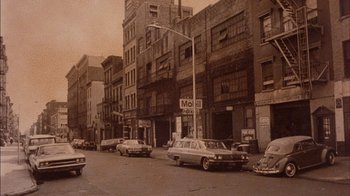 Movie still from “Fritz the Cat” (1972), directed by Ralph Bakshi – A vintage photo of cars parked on the side of the street; Extreme Wide shot, High angle