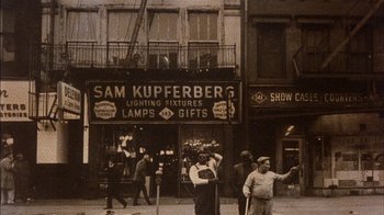 Movie still from “Fritz the Cat” (1972), directed by Ralph Bakshi – An old photo of people walking on the sidewalk; Wide shot, High angle