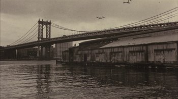 Movie still from “Fritz the Cat” (1972), directed by Ralph Bakshi – A bridge over a body of water near a city; Extreme Wide shot, Low angle