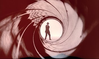 Movie still from “From Russia with Love” (1963), directed by Terence Young – A man is standing inside of a gun barrel; Wide shot, Low angle