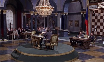 Movie still from “From Russia with Love” (1963), directed by Terence Young – A group of people sitting at a table in a room; Extreme Wide shot, High angle