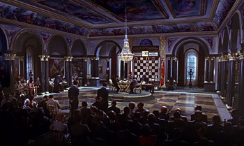 Movie still from “From Russia with Love” (1963), directed by Terence Young – A group of people sitting in front of a chess board in a room; Extreme Wide shot, High angle