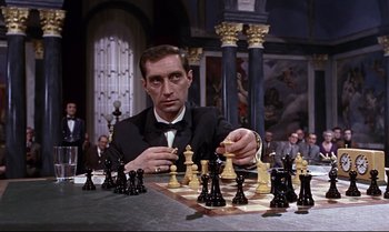 Movie still from “From Russia with Love” (1963), directed by Terence Young – A man in a suit and tie playing a game of chess; Close Up shot, High angle