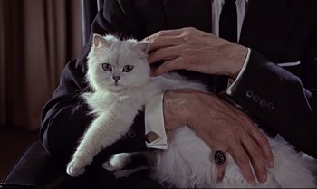 Movie still from “From Russia with Love” (1963), directed by Terence Young – A man holding a white fluffy cat in his lap; Medium shot, Over the shoulder angle