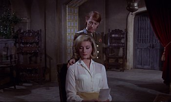 Movie still from “From Russia with Love” (1963), directed by Terence Young – A man and a woman are sitting in a room; Medium shot, Over the shoulder angle
