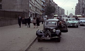 Movie still from “From Russia with Love” (1963), directed by Terence Young – An old car is parked on the side of the street; Wide shot, High angle