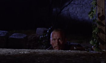 Movie still from “From Russia with Love” (1963), directed by Terence Young – A man is looking over a wall at the camera; Close Up shot, Low angle