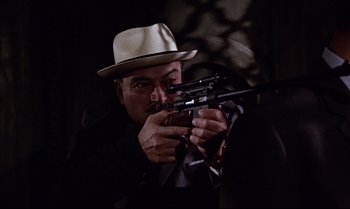 Movie still from “From Russia with Love” (1963), directed by Terence Young – A man in a fedora holding a gun in a dark room; Close Up shot, High angle