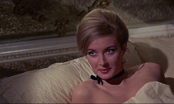 Movie still from “From Russia with Love” (1963), directed by Terence Young – A woman with a bow tie sitting on a couch; Close Up shot, High angle