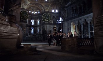 Movie still from “From Russia with Love” (1963), directed by Terence Young – A group of people standing inside of an old building; Extreme Wide shot, High angle