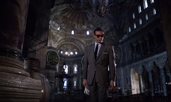 Movie still from “From Russia with Love” (1963), directed by Terence Young – A man in a suit and sunglasses in a church; Wide shot, Low angle