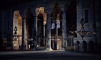 Movie still from “From Russia with Love” (1963), directed by Terence Young – A large building with many pillars and arches in the dark; Extreme Wide shot, High angle