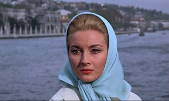 Movie still from “From Russia with Love” (1963), directed by Terence Young – A woman wearing a head scarf standing in front of a body of water; Close Up shot, Low angle