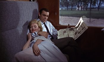 Movie still from “From Russia with Love” (1963), directed by Terence Young – A man and a woman sitting next to each other on a train; Medium shot, Low angle