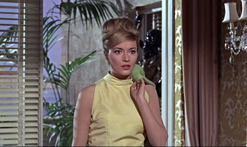 Movie still from “From Russia with Love” (1963), directed by Terence Young – A beautiful woman in a yellow dress holding a green bird; Close Up shot, Low angle
