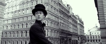 Movie still from “The Walk” (2015), directed by Robert Zemeckis – A man wearing a top hat standing in front of a building; Medium shot, Low angle