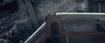 Movie still from “The Walk” (2015), directed by Robert Zemeckis – A man standing on a platform in the middle of a building; Wide shot, Overhead angle