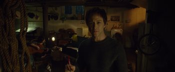 Movie still from “The Walk” (2015), directed by Robert Zemeckis – A man holding a pen in his hand in a dark room; Medium shot, High angle