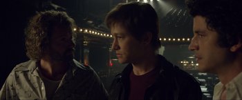 Movie still from “The Walk” (2015), directed by Robert Zemeckis – A man standing next to another man in a dark room; Close Up shot, Over the shoulder angle