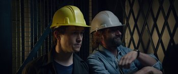 Movie still from “The Walk” (2015), directed by Robert Zemeckis – A couple of men in hard hats sitting next to each other; Close Up shot, Low angle