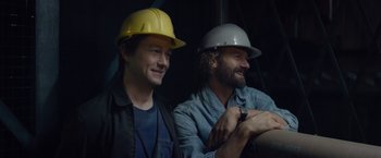 Movie still from “The Walk” (2015), directed by Robert Zemeckis – A couple of men sitting next to each other wearing hard hats; Close Up shot, Low angle