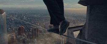 Movie still from “The Walk” (2015), directed by Robert Zemeckis – A person is standing on a rope above a city; Wide shot, High angle