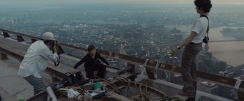 Movie still from “The Walk” (2015), directed by Robert Zemeckis – A man sitting on the side of a building on top of a building; Wide shot, High angle