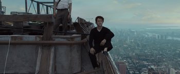 Movie still from “The Walk” (2015), directed by Robert Zemeckis – A man sitting on the side of a building on top of a building; Wide shot, High angle