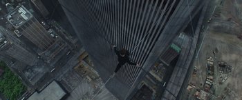Movie still from “The Walk” (2015), directed by Robert Zemeckis – A man hanging from a rope in the middle of a tall building; Wide shot, Overhead angle