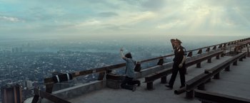 Movie still from “The Walk” (2015), directed by Robert Zemeckis – Two people standing on top of a bench looking at a city; Extreme Wide shot, High angle