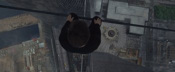 Movie still from “The Walk” (2015), directed by Robert Zemeckis – A man standing on a ledge looking down at a building; Wide shot, Overhead angle
