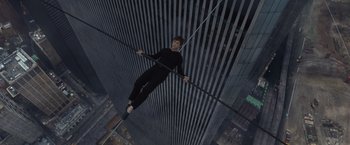 Movie still from “The Walk” (2015), directed by Robert Zemeckis – A man hanging from a metal pole in the middle of a building; Wide shot, Overhead angle
