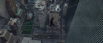 Movie still from “The Walk” (2015), directed by Robert Zemeckis – A cat is hanging on to a wire in the middle of a city; Extreme Wide shot, Overhead angle