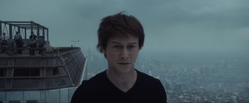 Movie still from “The Walk” (2015), directed by Robert Zemeckis – A young man is standing in front of a city skyline; Close Up shot, Low angle