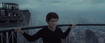 Movie still from “The Walk” (2015), directed by Robert Zemeckis – A man holding onto a metal pole in front of a city; Medium shot, Low angle