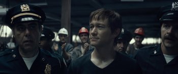 Movie still from “The Walk” (2015), directed by Robert Zemeckis – A group of people standing in a room; Close Up shot, Over the shoulder angle