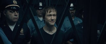 Movie still from “The Walk” (2015), directed by Robert Zemeckis – A man standing in front of a group of police officers behind bars; Close Up shot, Over the shoulder angle