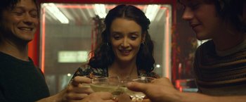 Movie still from “The Walk” (2015), directed by Robert Zemeckis – A woman is holding a glass of wine and smiling; Close Up shot, Over the shoulder angle