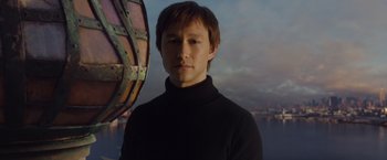 Movie still from “The Walk” (2015), directed by Robert Zemeckis – A man in a black sweater standing in front of a boat in the water; Close Up shot, Low angle