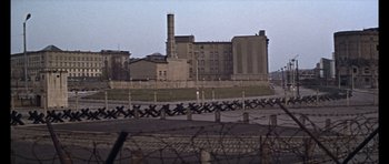 Movie still from “Funeral in Berlin” (1966), directed by Guy Hamilton – A view of an industrial area from the side of a fence; Extreme Wide shot, High angle