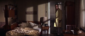 Movie still from “Funeral in Berlin” (1966), directed by Guy Hamilton – A man standing in front of a bed in a room; Wide shot, Low angle