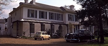 Movie still from “Funeral in Berlin” (1966), directed by Guy Hamilton – Two cars are parked in front of a large house; Extreme Wide shot, Low angle